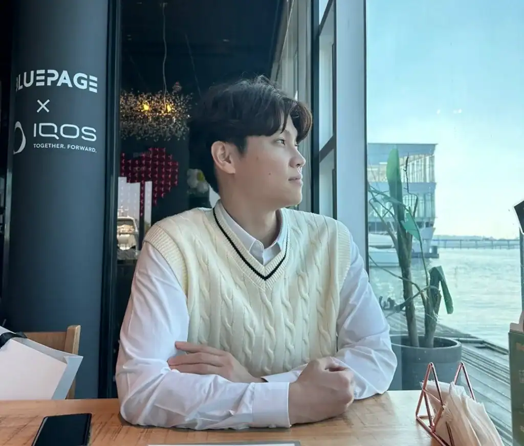 창가에 앉아 창밖 풍경을 바라보는 젊은 남성의 모습.