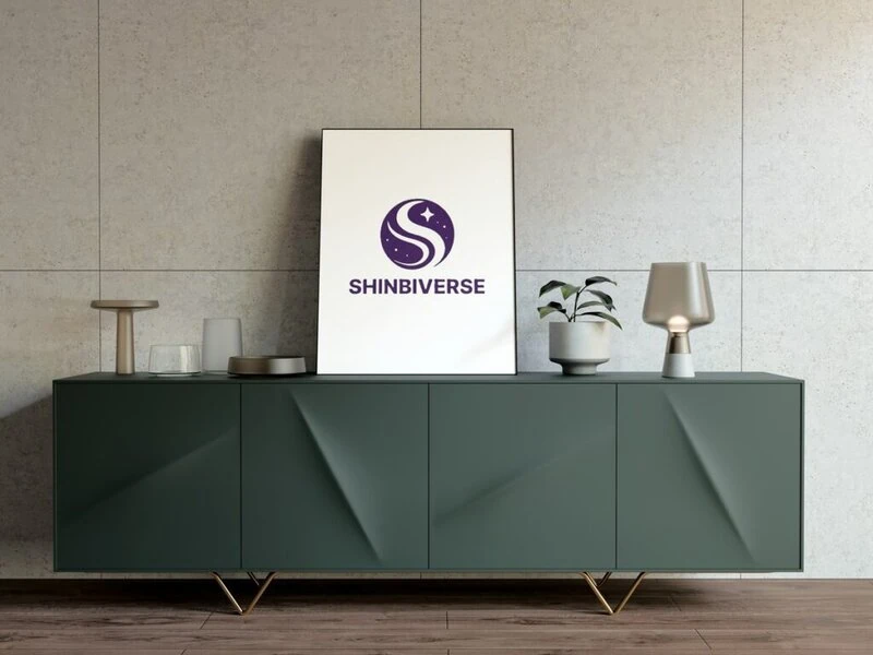 On an elegant green table sits a white frame displaying the 'Shinbibus' logo, which harmoniously combines the universe and the letter 'S' in purple.