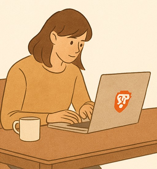 Woman working on a laptop, with a coffee cup beside her